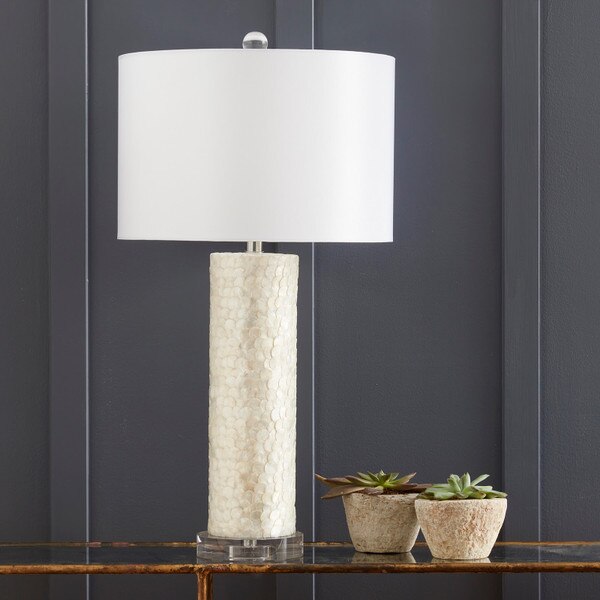 Scalloped capiz lamp on a table in front of a blue wall